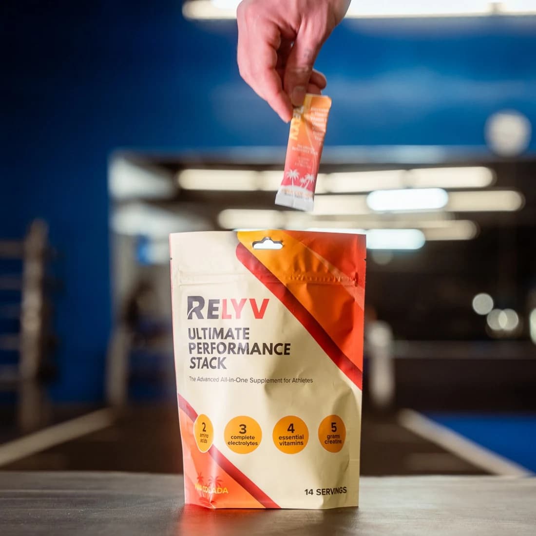 Hand lowering a Relyv stick toward the Ultimate Performance Stack pouch in a gym